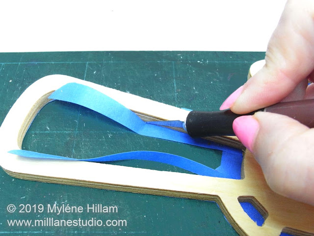 Using a craft knife to trim the tape to the shape of the wood.