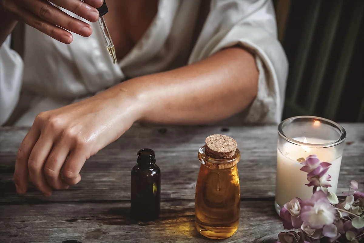 close-up of emale's hands applying beauty oil on to the skin