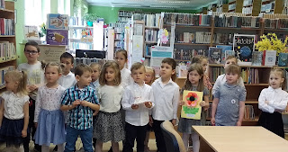 Grupa dzieci z przedszkola stoi przed ladą biblioteczną.