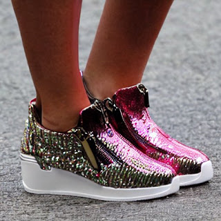 Woman wearing fashionable pink lady's disco-style zip-up sneakers with a heel. There are no shoelaces.