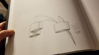 An pencil drawing in a sketchbook of a floor lamp, with 3 cylindrical shades hanging down.