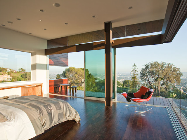 Picture of the large bed in the bedroom with red swaying chair and beautiful city views