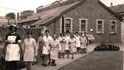 A photograph showing a group of nurses and patients walking outside Ely. ‘outside of Ely Hospital’ The Peoples Collection- copyright Mona Hussey.