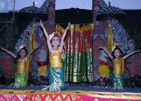 A group of Balinese dancers in traditional costumes are performing a traditional dance. The dancers are moving gracefully and their expressions are serene.