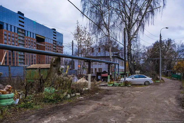 Припаркованная машина под трубой на фоне стройки многоэтажки