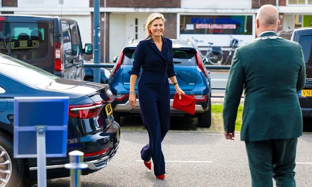 Queen Maxima wore a navy blue wrap front jumpsuit by Natan Couture. She wore red suede pumps