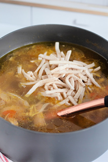 frozen noodles being stirred into a soup pot.