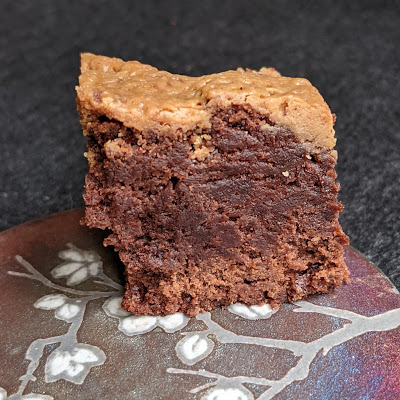 Side view of fudgy brownie with lighter brown peanut butter layer on top