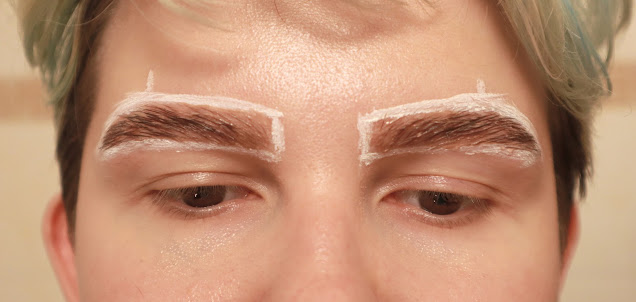A photo of eyebrows with a white contour around them, covered in tint