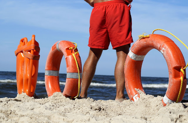 sauveteur aquatique les pieds dans le sable avec des bouées de sauvetage
