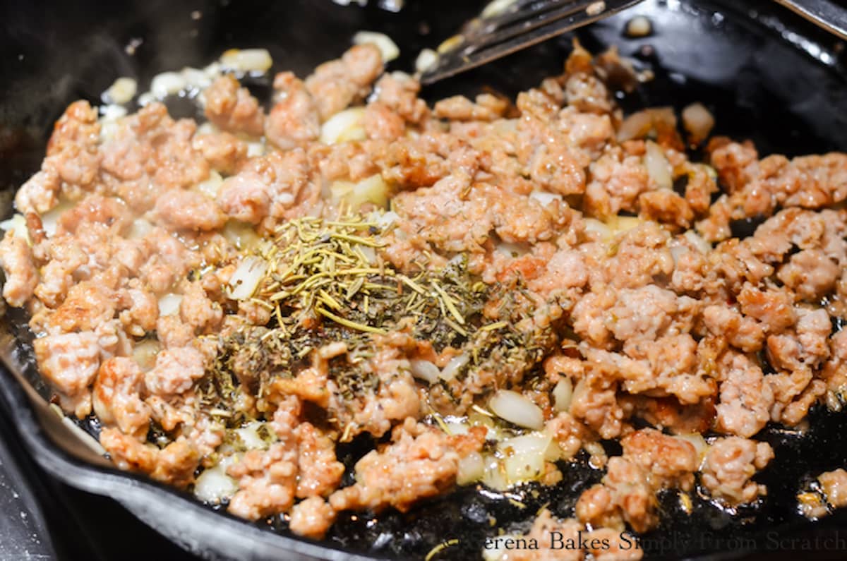 Brown Sausage and herbs in a cast iron skillet.