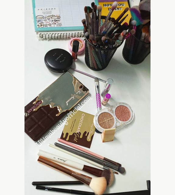 Different makeup products and makeup brushes on a desk