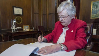 Alabama Gov. Kay Ivey signs a bill that virtually outlaws abortion in the state.