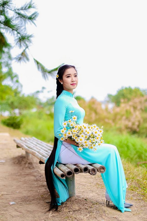 Thiếu nữ áo dài xanh tóc dài ngồi ôm hoa
