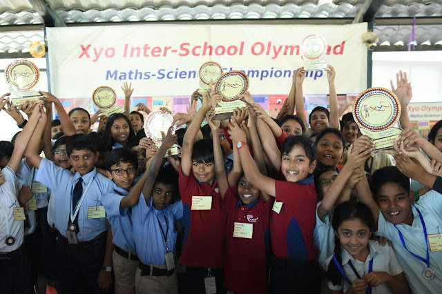 Excited students pose in front of the camera after winning trophies in the Olympiad.