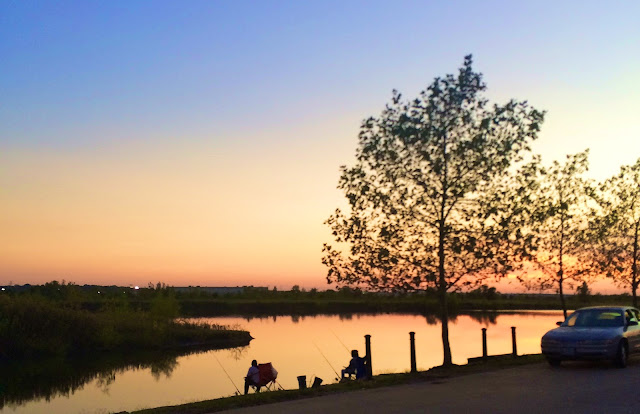 sunset over a lake with fishermen in the foreground