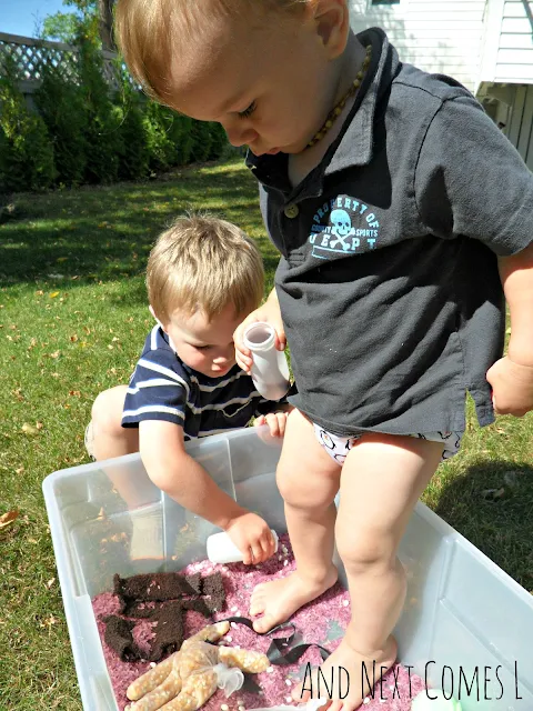 Toddler standing in a Gruffalo sensory bin with dyed rice