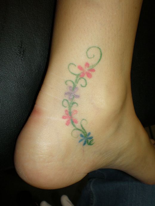 Vine of small flowers tattooed on ankle.