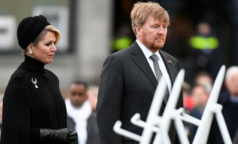 Queen Maxima wore a black wool high collar cape coat. Black leather handbag. Pearl drop earrings and diamond brooch. Gripoix earrings