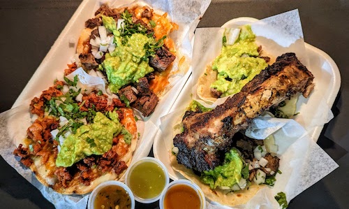 Two tacos and two lorenzas, with a charred rib laid across the tacos