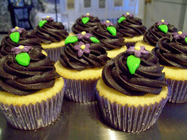 Yellow Cupcakes with Dark Chocolate Frosting and Purple Flowers