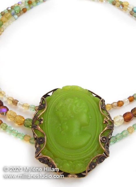 Lime green resin cameo wrapped with a filigree brass stamping, strung with light green, yellow and brown crystals.