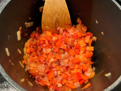 chopped red pepper, onion, garlic and chilli mixed with tomato puree in a saucepan