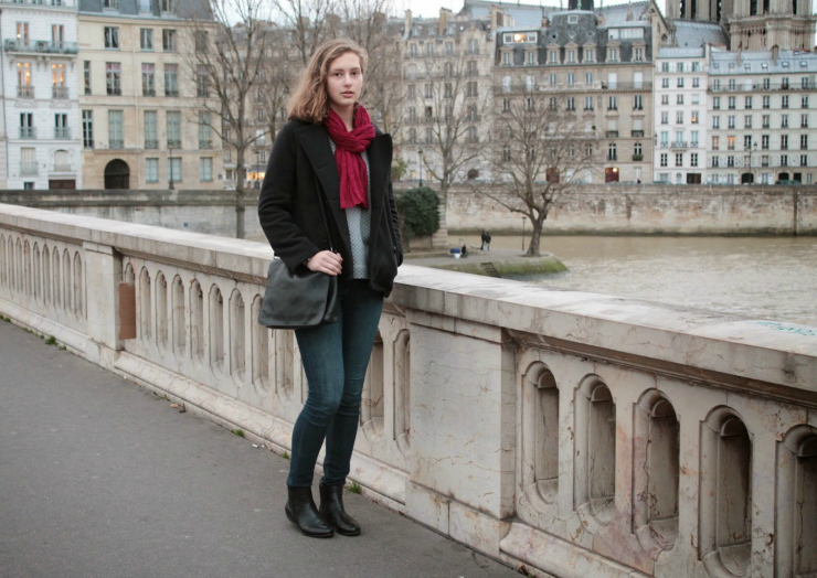 Parisian style of black pea coat, fashionable sweatshirt and jeans with a black leather bag