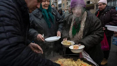 Vizinhos recebem comida grátis de uma cozinha de sopa em Bucha, nos arredores de Kiev, na Ucrânia.