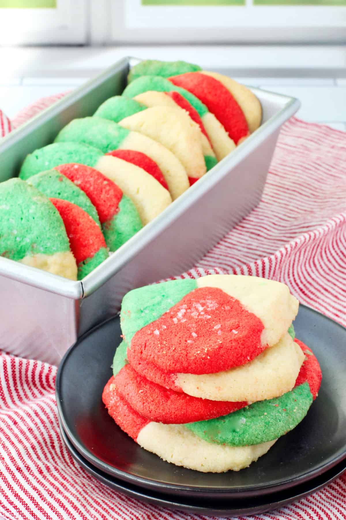 Red, White, and Green Polvorones (Mexican Sugar Cookies) in a bread pan and on plates.