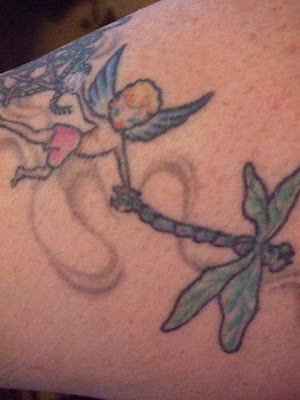 Flying fairy and dragonfly tattoo on the arm.