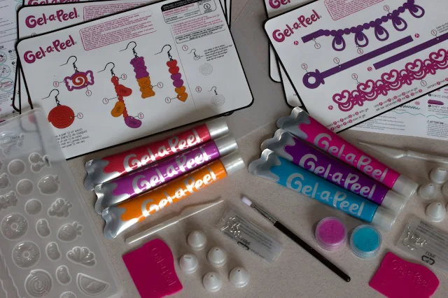 The contents of two Gel-a-Peel kits used to decorate the cards. There are patterns, a mould, 6 tubes of gel, earring , fuzz, nozzles, scrapers and a brush