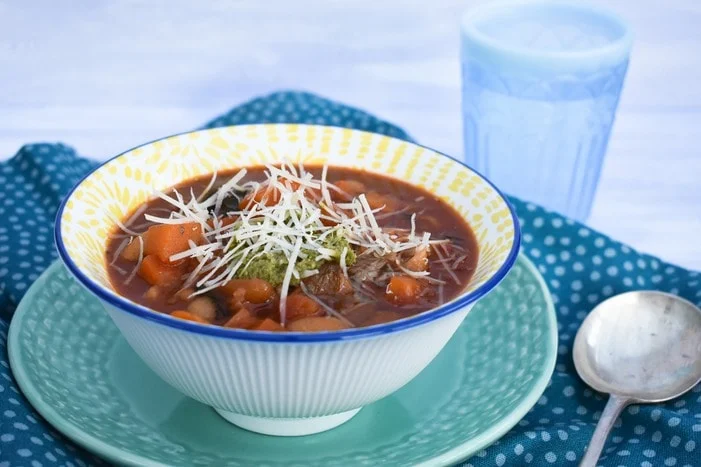 Winter Minestrone Soup topped with pesto and vegan parmesan