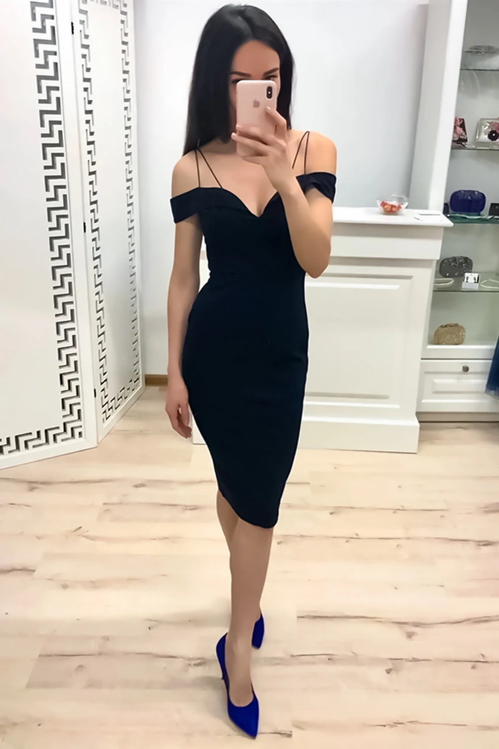 woman in a tight evening dress is posing in the room and taking a selfie