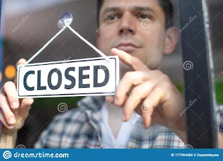 Small business owners holding a sign that says “Business Closed”
