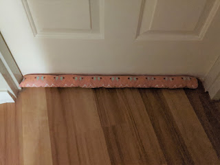 The same closed door as the last photo, but now with a pink fabric snake covering the gap snuggly.