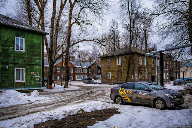 Припаркованные машины среди деревянных домов