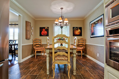 a traditional dining room with neutral hues and wood accent floor surrounded with bright fruits painting