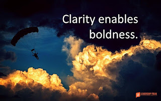 picture of clouds with a person paragliding through them with the words "clarity enables boldness."