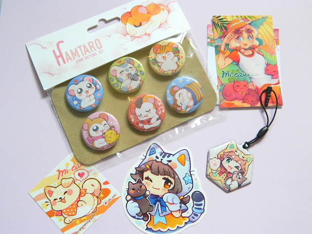 A haul from a store called Mi-eau, featuring badges, stickers and a charm