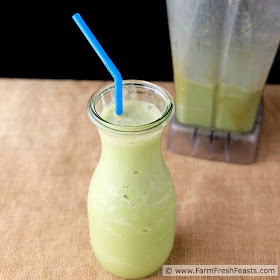 image of a peanut butter, spinach, and banana smoothie in a glass with a blender behind it
