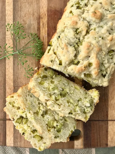 A loaf of dill pickle quick bread on a cutting board with slices.