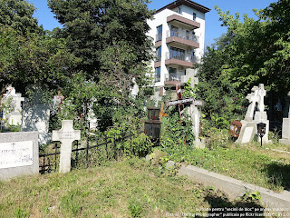 poza arata un cimitir cu cateva morminte cu cruci aflate sub un bloc rezidential