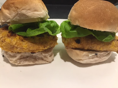 2 chickpea burgers in white buns with lettuce on a white plate