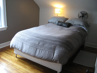 midway picture of bedroom with painted walls, new duvet cover and plain white sloped wall behind headboard