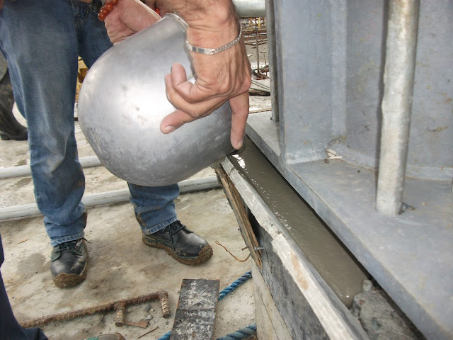 Pouring the non-shrink grout between the concrete pedestal and steel plate gap 