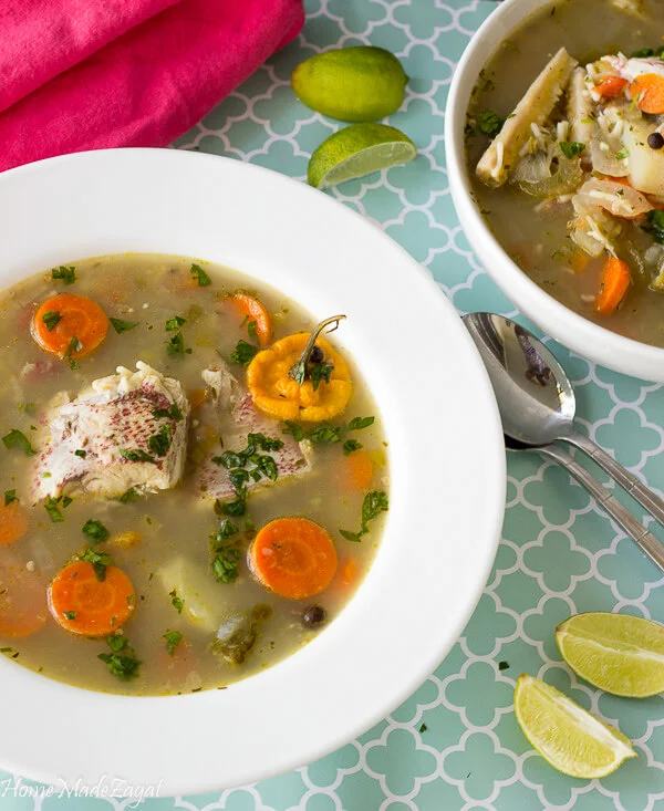 A full bowl of finished fish broth in a white bowl on a blue and white backdrop.