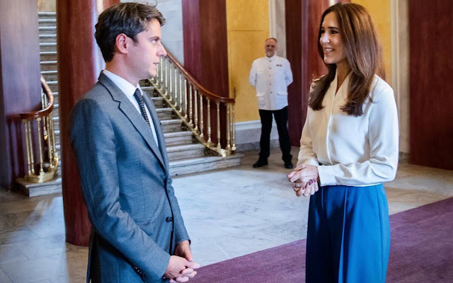 Crown Princess Mary wore a Bowery ivory stretch silk blouse by The Fold London. Princess Mary wore blue wide-leg pants