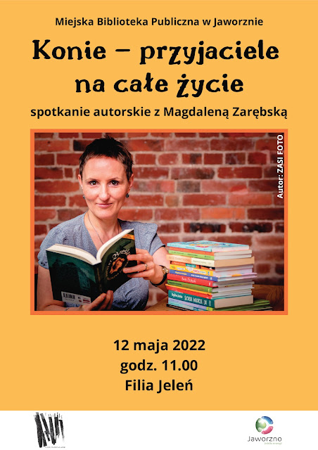 Tło: pomarańczowe. Na środku duże zdjęcie, przestawiające Magdalenę Zarębską. Autorka siedzi przy stoliku, na którym leży stos książek, trzymając w rękach książkę "Projekt Breslau". Tłem zdjęcia jest ściana z czerwonej cegły. Powyżej zdjęcia tekst: Miejska Biblioteka Publiczna w Jaworznie - Filia Jeleń "Konie - przyjaciele na całe życie" spotkanie autorskie z Magdaleną Zarębską, poniżej zdjęcia tekst: 12 maja 2022 godz. 11.00 Filia Jeleń. Logo Biblioteki w Jaworznie, Miasta Jaworzna.