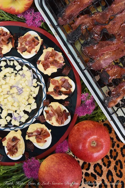 Plate of finished deviled eggs on a deviled eggs plate with apples.